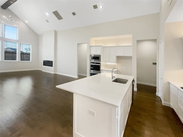 kitchen with appliances with stainless steel finishes, sink, an island with sink, white cabinetry, and high vaulted ceiling