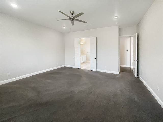 unfurnished bedroom featuring ensuite bathroom, dark carpet, and ceiling fan