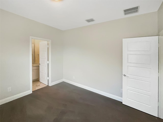unfurnished bedroom featuring ensuite bathroom, visible vents, and baseboards