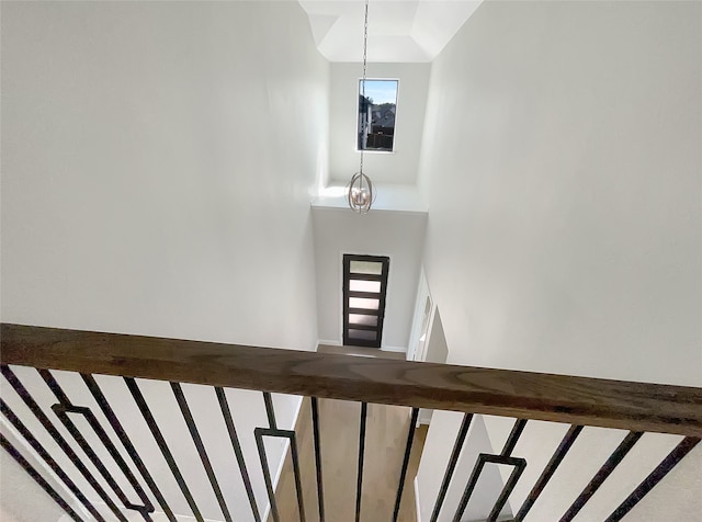 stairway featuring lofted ceiling and a notable chandelier