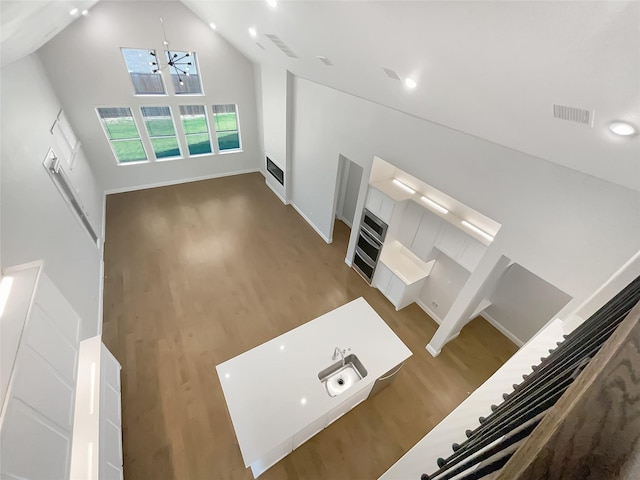 unfurnished living room featuring visible vents, recessed lighting, wood finished floors, baseboards, and high vaulted ceiling