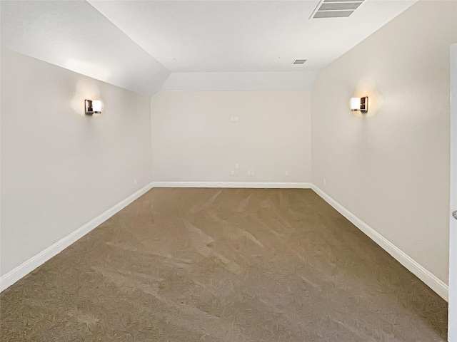 unfurnished room featuring baseboards, visible vents, dark colored carpet, and lofted ceiling