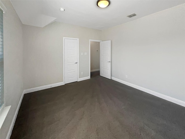 unfurnished bedroom featuring baseboards, visible vents, and dark carpet