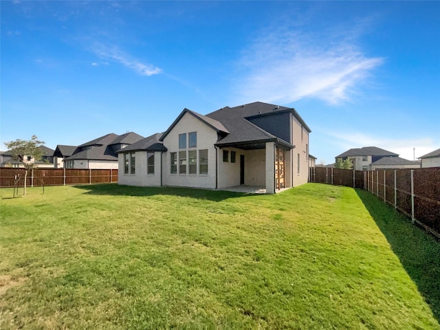 back of property featuring a lawn, a patio, stucco siding, and a fenced backyard