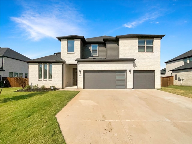 prairie-style house with fence, driveway, a front yard, and an attached garage