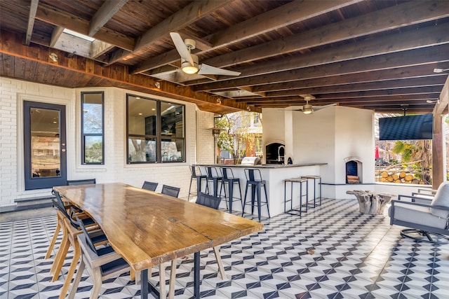 view of patio featuring ceiling fan, a bar, and an outdoor fireplace