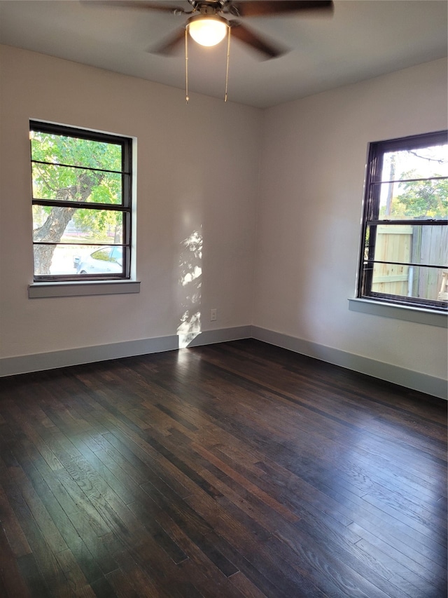 empty room with dark wood-type flooring, plenty of natural light, and ceiling fan