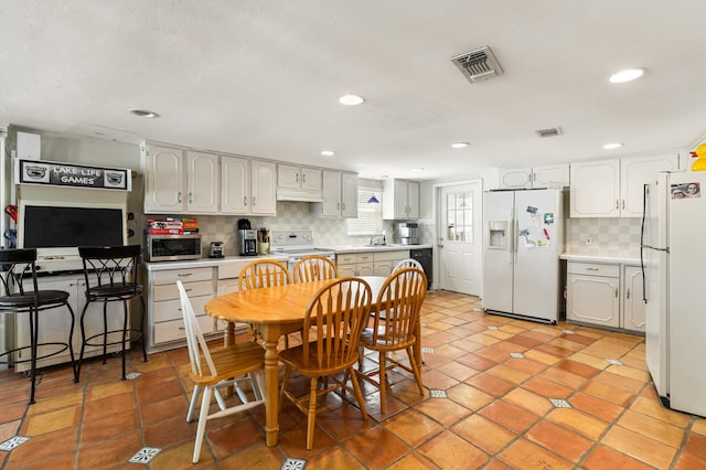 kitchen featuring tasteful backsplash, light tile patterned floors, white cabinetry, sink, and white appliances