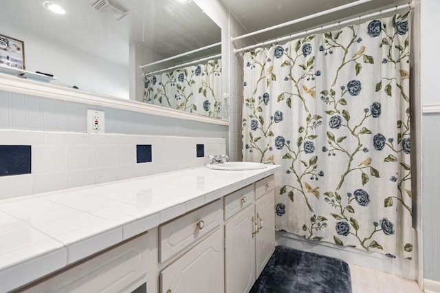 bathroom with vanity, curtained shower, tile patterned flooring, and backsplash