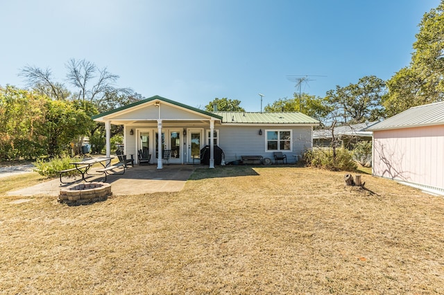 back of property featuring a patio area, an outdoor fire pit, and a lawn