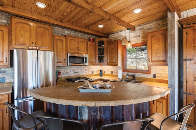 kitchen with stainless steel appliances, sink, a kitchen bar, and pendant lighting