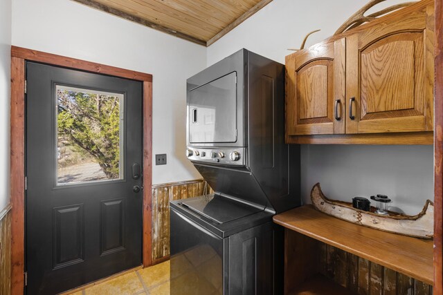 laundry room with cabinets, wood ceiling, and stacked washer / drying machine