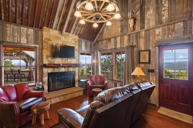 living room featuring a stone fireplace, a healthy amount of sunlight, and wood walls