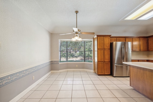 kitchen with a textured ceiling, stainless steel refrigerator, ceiling fan, and light tile patterned flooring