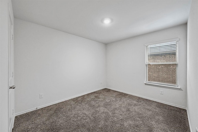 spare room featuring dark colored carpet