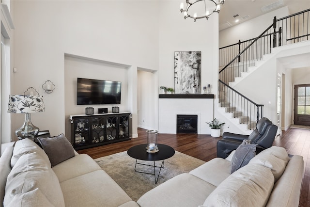 living room with a chandelier, hardwood / wood-style floors, and a towering ceiling