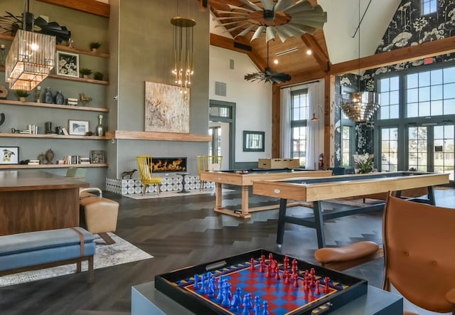 recreation room featuring hardwood / wood-style flooring, beam ceiling, high vaulted ceiling, and a chandelier