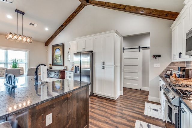 kitchen with stainless steel appliances, hanging light fixtures, a barn door, and white cabinets