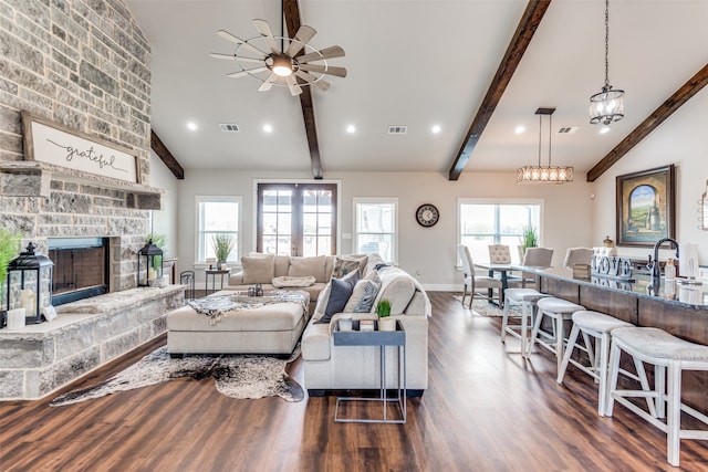 living room with ceiling fan, vaulted ceiling with beams, dark wood-type flooring, a fireplace, and sink