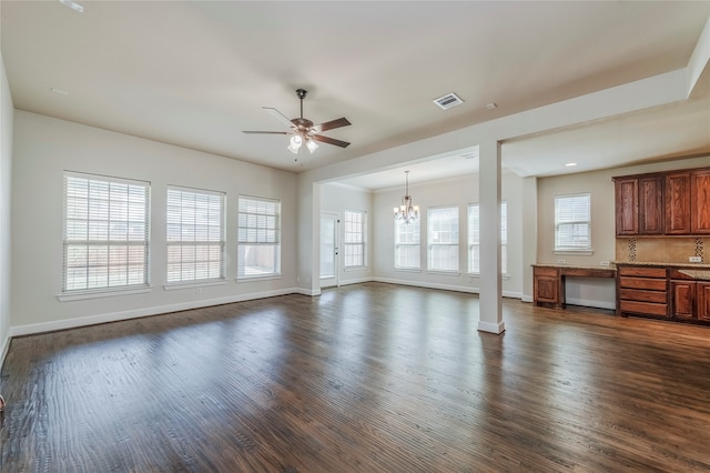 unfurnished living room with a healthy amount of sunlight, dark wood-type flooring, and ceiling fan with notable chandelier