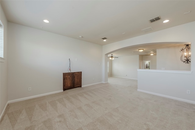 spare room featuring light colored carpet and ceiling fan with notable chandelier