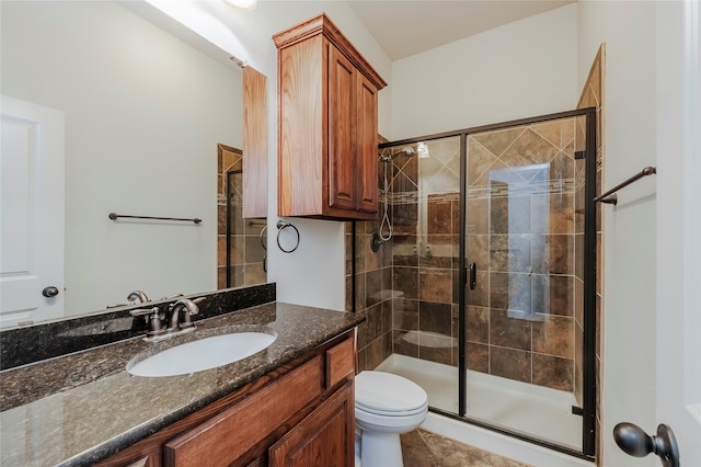 bathroom with vanity, toilet, and a shower with door