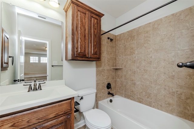 full bathroom featuring vanity, tiled shower / bath, and toilet