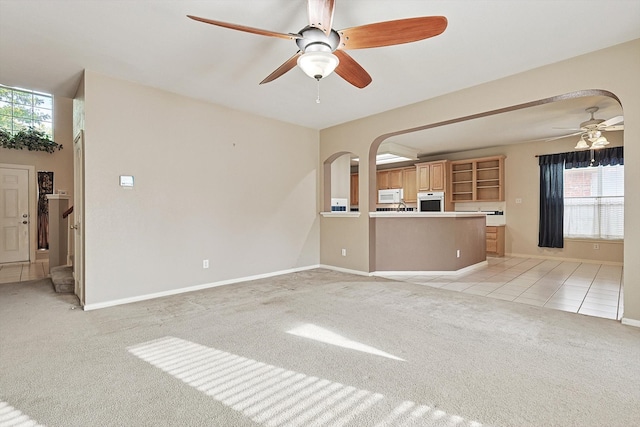 unfurnished living room featuring light carpet, a healthy amount of sunlight, and ceiling fan