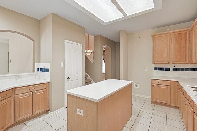 kitchen featuring light brown cabinets, decorative backsplash, light tile patterned floors, and a kitchen island