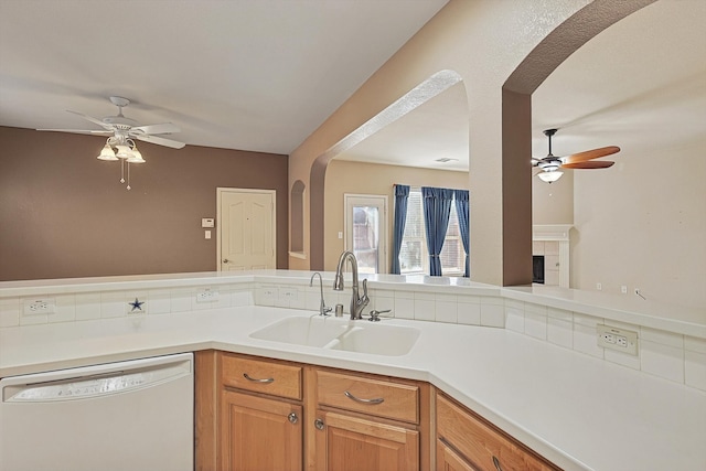 kitchen with ceiling fan, white dishwasher, sink, and a tile fireplace