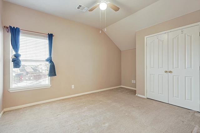 unfurnished bedroom with ceiling fan, lofted ceiling, multiple windows, and light colored carpet