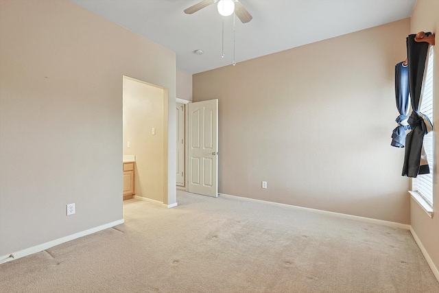 unfurnished bedroom featuring ensuite bath, light colored carpet, and ceiling fan