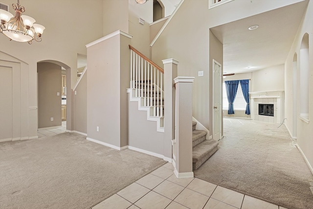 staircase featuring carpet floors, a chandelier, and a fireplace