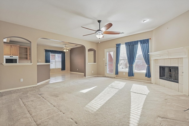 unfurnished living room featuring light carpet, a fireplace, and ceiling fan