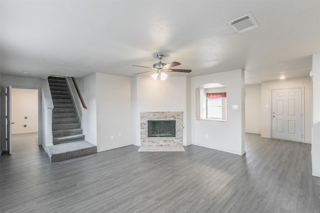 unfurnished living room with a fireplace, dark hardwood / wood-style floors, and ceiling fan