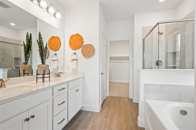 bathroom with hardwood / wood-style floors, vanity, and shower with separate bathtub