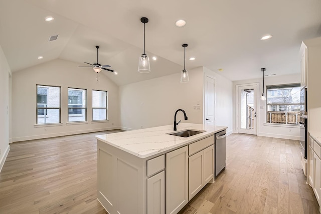 kitchen with decorative light fixtures, white cabinetry, an island with sink, sink, and light stone counters