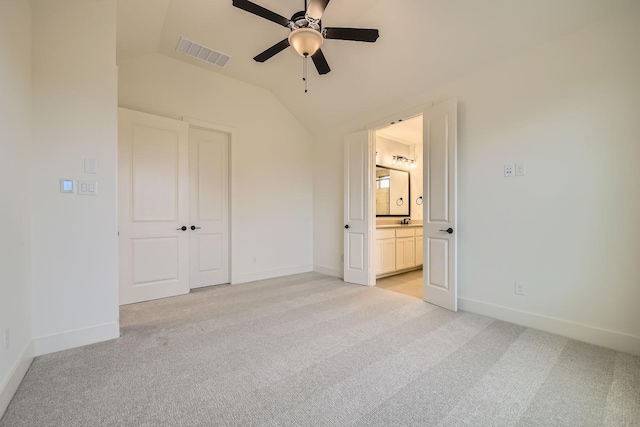 unfurnished bedroom with light colored carpet, ceiling fan, vaulted ceiling, and ensuite bath