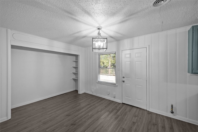 entrance foyer with a textured ceiling, an inviting chandelier, and dark hardwood / wood-style flooring