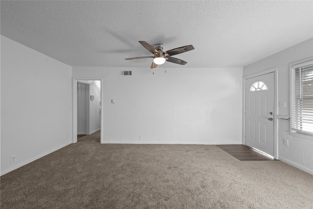 entryway featuring dark colored carpet, a textured ceiling, and ceiling fan