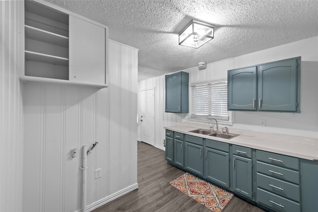 kitchen featuring blue cabinets, sink, dark hardwood / wood-style floors, and a textured ceiling