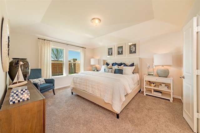 bedroom featuring light colored carpet and a tray ceiling