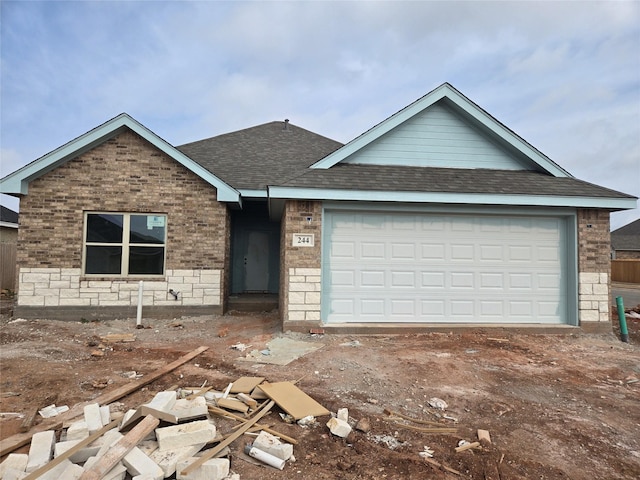 single story home with a garage, roof with shingles, and brick siding