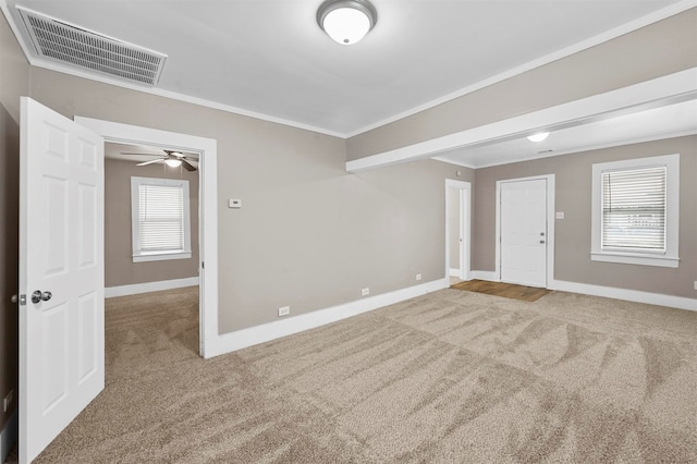 carpeted empty room with crown molding, ceiling fan, and a wealth of natural light