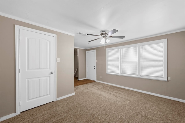 empty room with ornamental molding, carpet floors, and ceiling fan