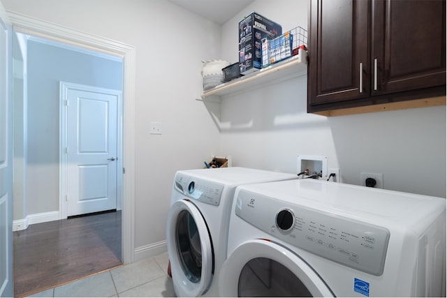 laundry room with light hardwood / wood-style flooring, washing machine and dryer, and cabinets