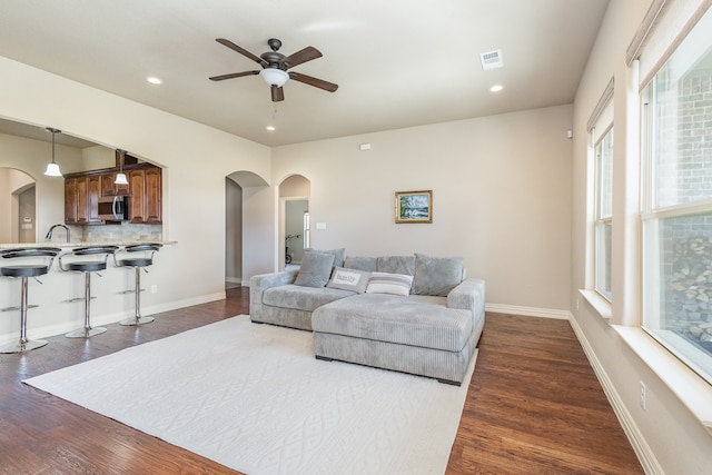 living room with dark wood-type flooring and ceiling fan