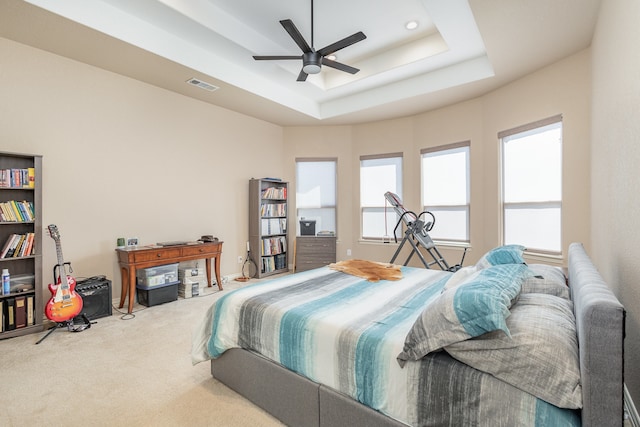 bedroom featuring ceiling fan, a tray ceiling, and carpet floors