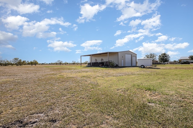 view of yard featuring a rural view, an outbuilding, and a garage