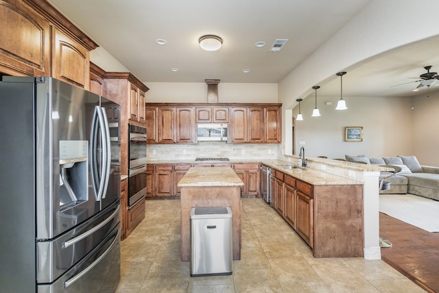 kitchen with sink, kitchen peninsula, hanging light fixtures, stainless steel appliances, and decorative backsplash